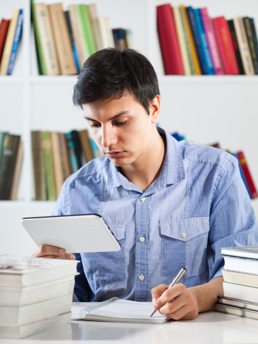 Student looks at tablet while taking notes