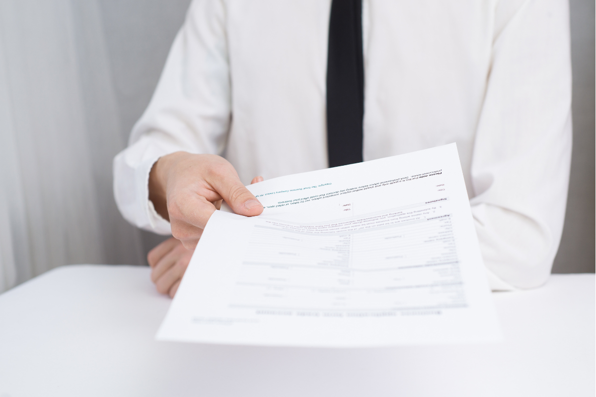 Man in white shirt hands over piece of paper